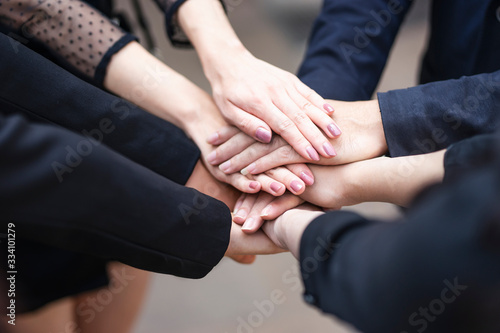 Fototapeta Naklejka Na Ścianę i Meble -  close up top view of workers putting hands together piling on top of one another representing teamwork, community help and support within the small business or company within an office environment