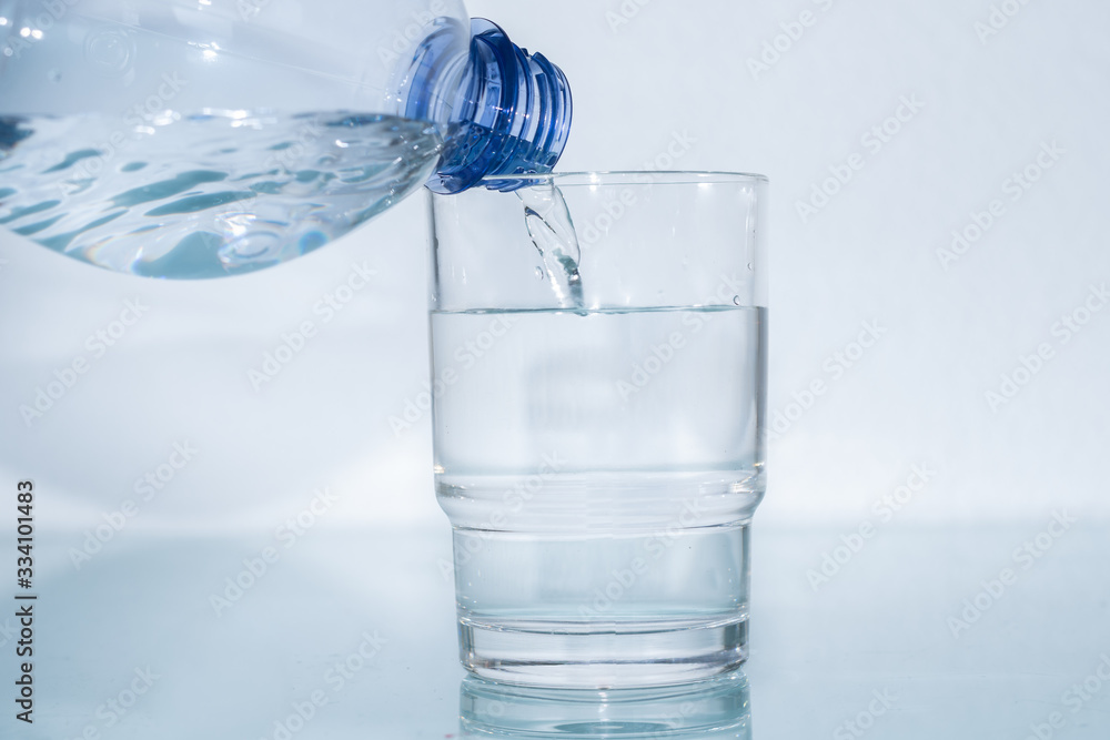 Mineralwasser aus Plastikflasche in das Glas giessen Mineralwasser aus Plastikflasche in das Glas giessen