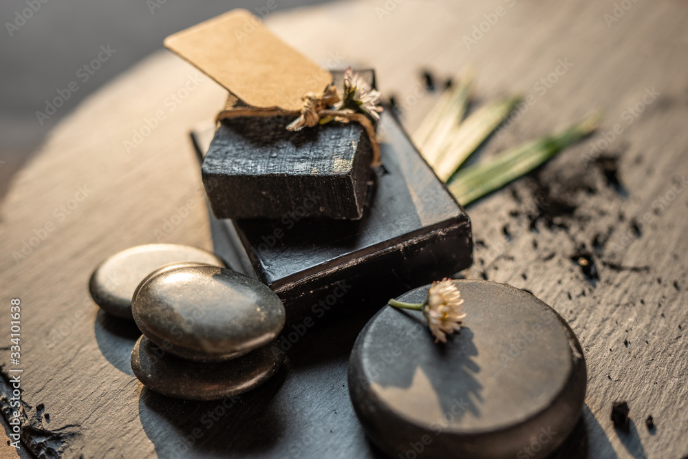 charcoal coal carbon black soap bar on a raw wood background lava stone spa skin care hygiene concept 