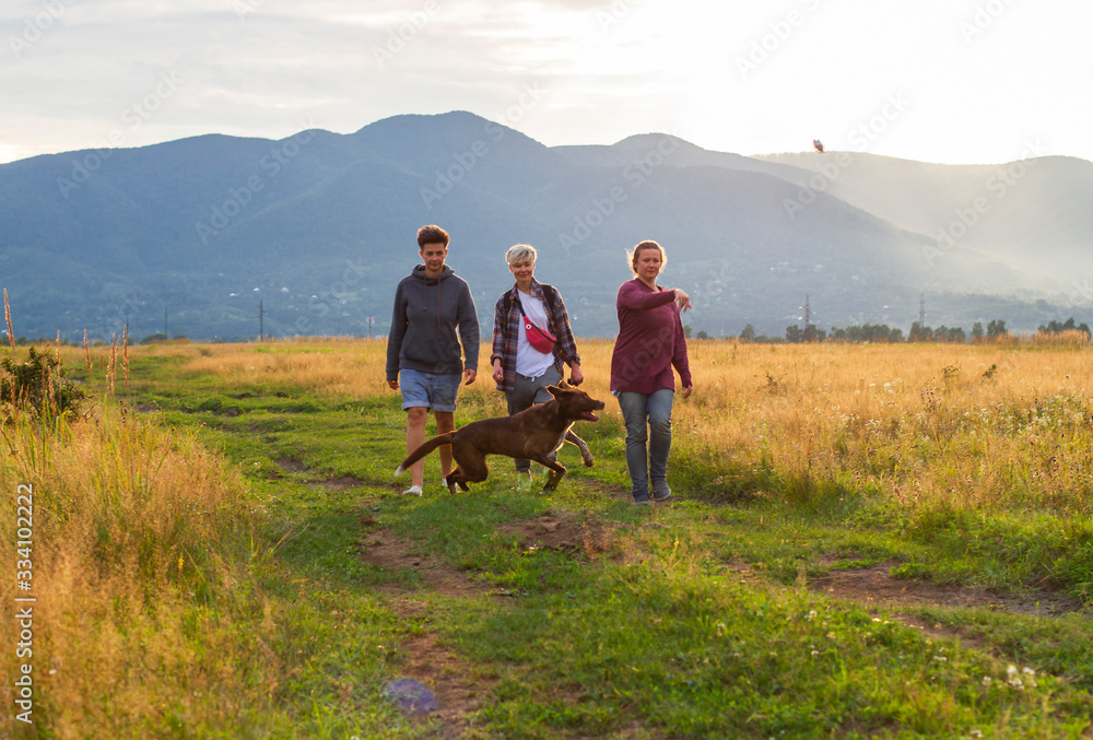 women walk with dogs on a background of mountains