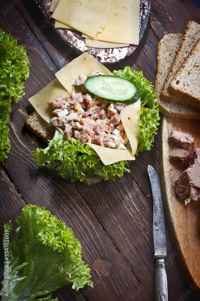 tuna fish sandwich on wooden table, with green salad, cheese and fresh vegetables tuna fish sandwich on wooden table, with green salad, cheese and fresh vegetables
