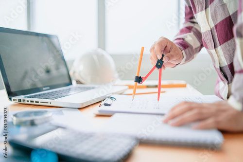 architect man with Architectural plans Laptop, calculator pencil pen and ruler on the table, Concept architects, engineer compass equipment on the desk with a blueprint in the office,Selective Focus