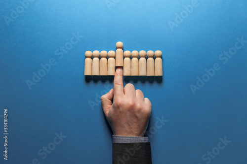 Foto Hand of businessman chooses best candidate among figures of hired people