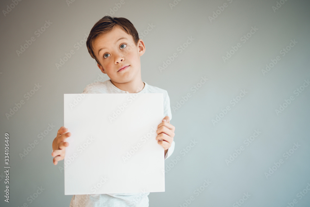 cool young boy is holding white sign in front of grey background during corona crisis cool young boy is holding white sign in front of grey background during corona crisis