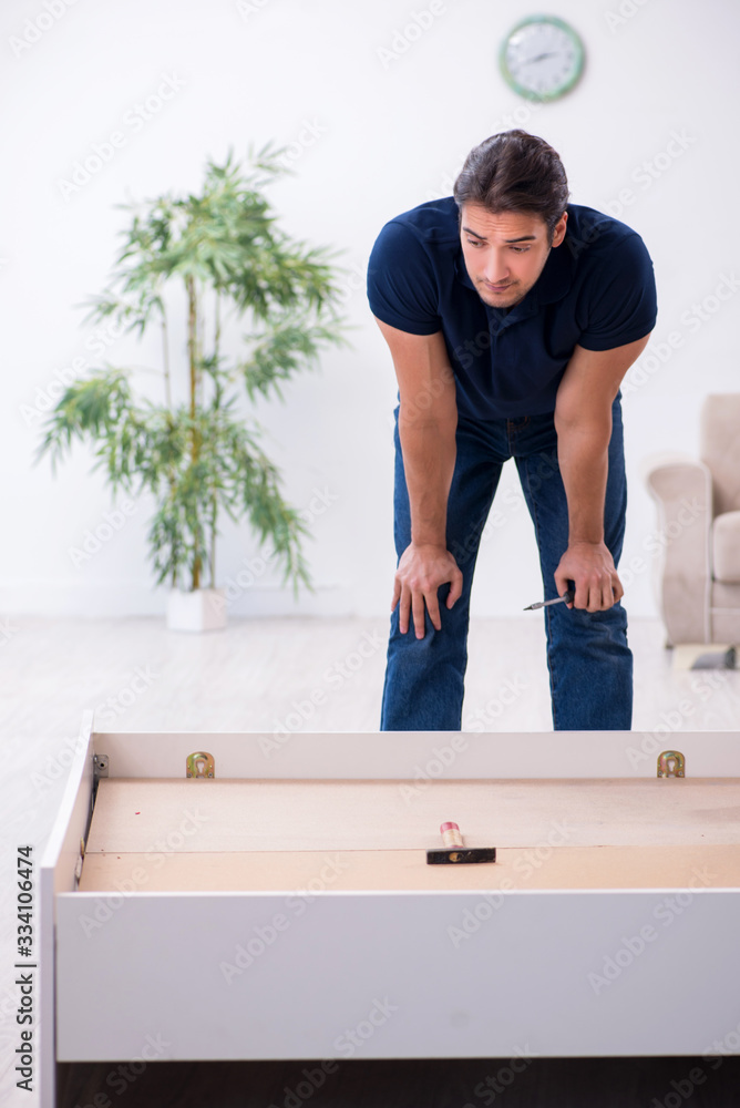 Fototapeta premium Young male contractor installing furniture at home