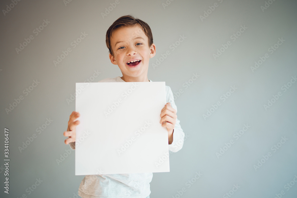 cool young boy is holding white sign in front of grey background during corona crisis cool young boy is holding white sign in front of grey background during corona crisis