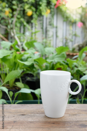 White coffee cup on wood plank in vegetable farm and flowers garden