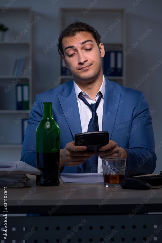 Alcohol addicted businessman working late in the office Alcohol addicted businessman working late in the office