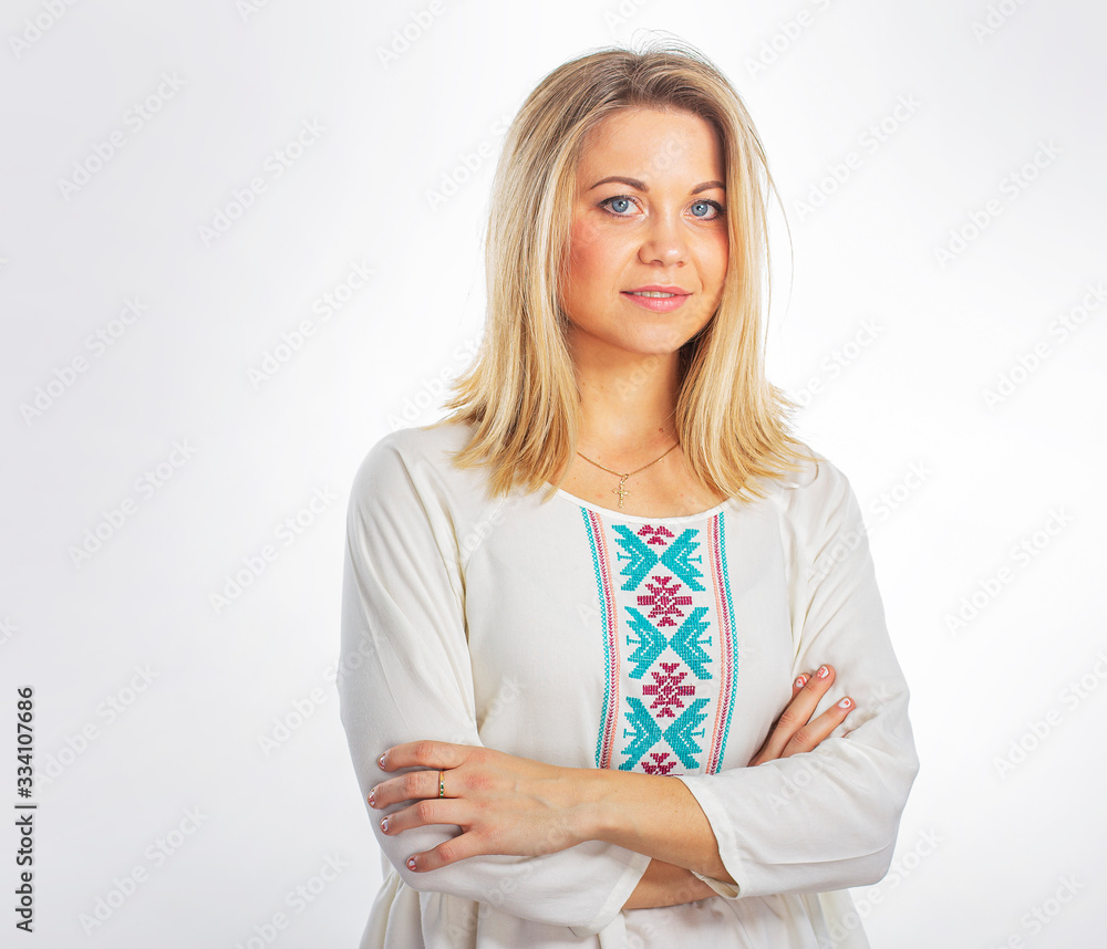 Isolated portrait of a young girl in a white embroidered blouse. Beautiful blonde in a closed pose. Lovely girl with blond hair.
