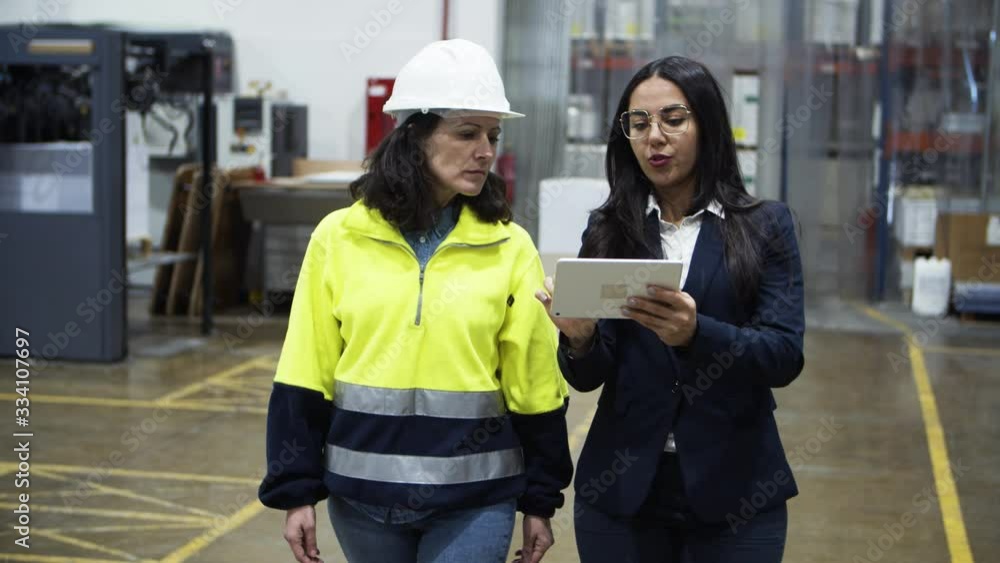 Concentrated project manager and technician walking with tablet. Focused professional factory worker listening instructions from boss. Manufacturing, technology concept Concentrated project manager and technician walking with tablet. Focused professional factory worker listening instructions from boss. Manufacturing, technology concept