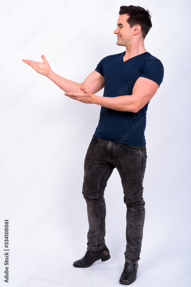 Full body shot of happy young handsome man showing something Full body shot of happy young handsome man showing something