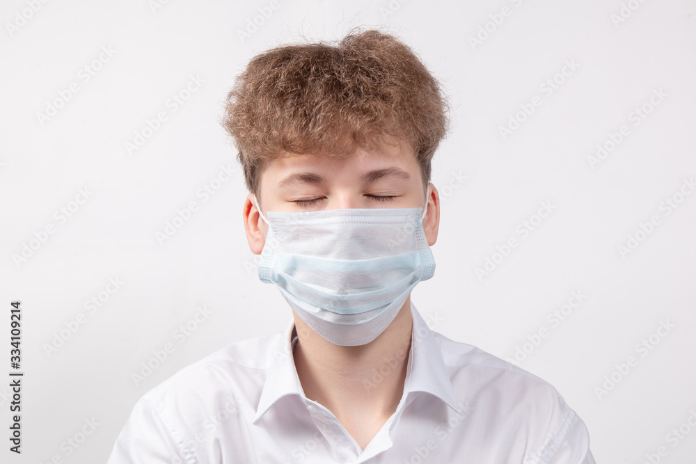 Teenager boy with eyes closed in protective medical mask to protect against the virus and coronavirus Teenager boy with eyes closed in protective medical mask to protect against the virus and coronavirus
