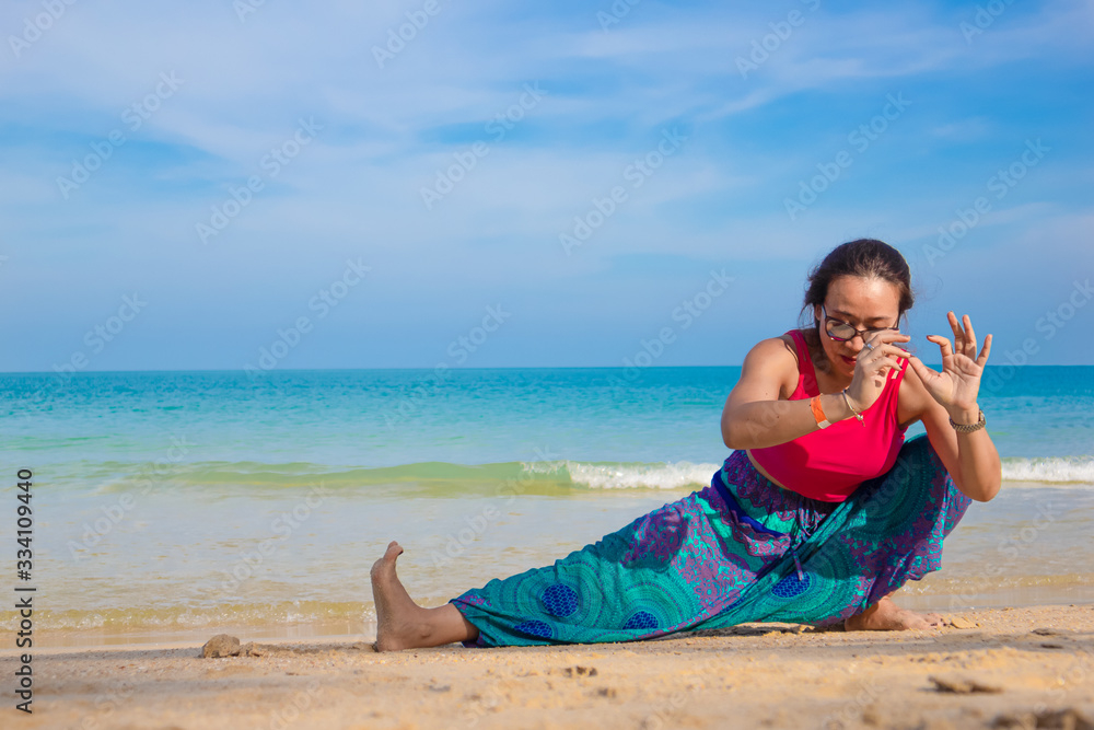 Asian Thai woman practicing yoga in Ao Thong Nai Pan Noi beach, Koh Phangan island, Thailand