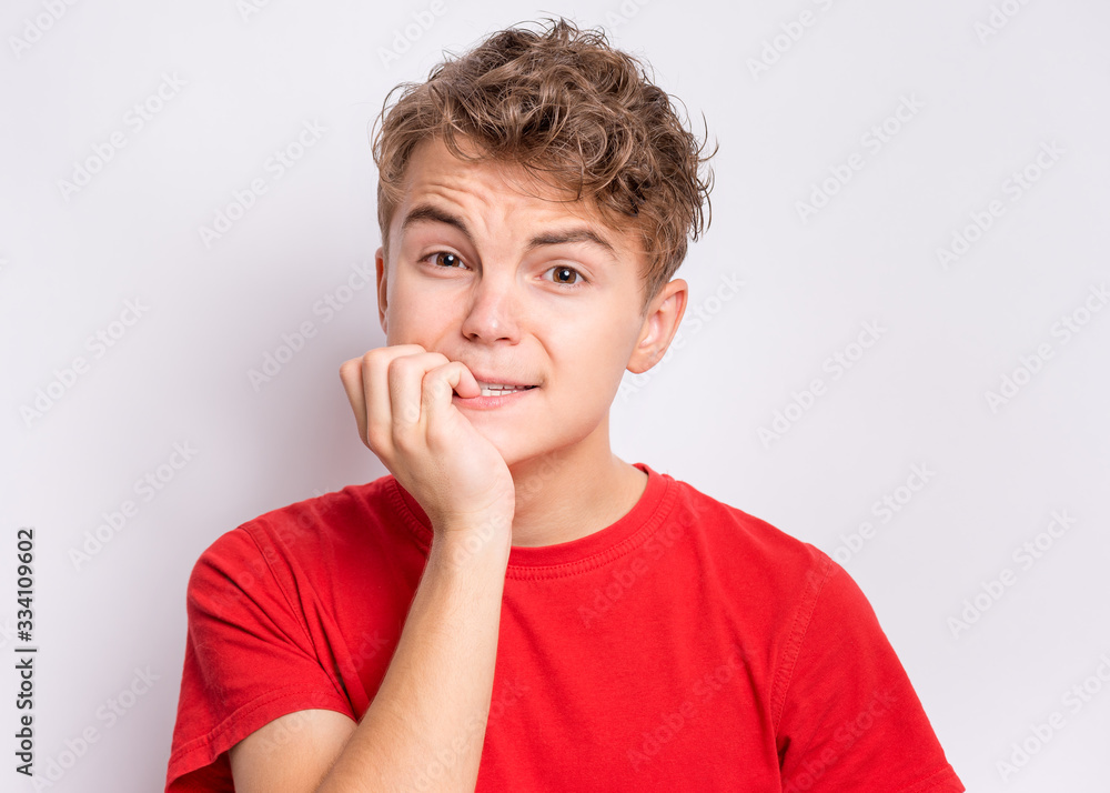 Portrait of unhappy teen boy looking stressed and nervous with hands on mouth biting nails. Funny guy something very frightened. Child gnaws his nails for fear, afraid of punishment. Portrait of unhappy teen boy looking stressed and nervous with hands on mouth biting nails. Funny guy something very frightened. Child gnaws his nails for fear, afraid of punishment.