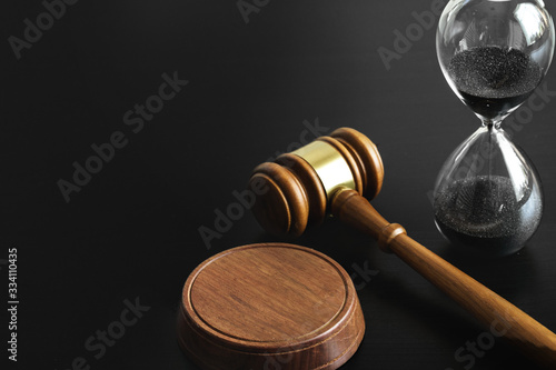 Court concept. Hourglass and judge gavel on table close up