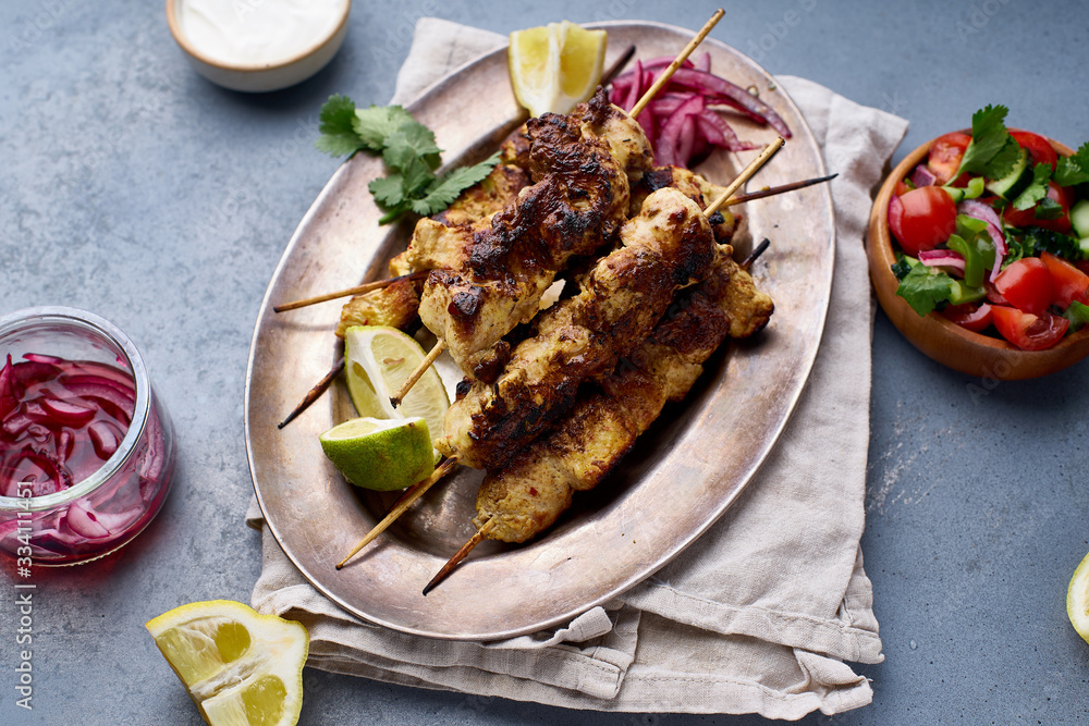 Chicken tikka kebab with marinated onion, fresh salad and yoghurt sauce. Traditional indian cuisine, delicious starter. Creative flatlay Chicken tikka kebab with marinated onion, fresh salad and yoghurt sauce. Traditional indian cuisine, delicious starter. Creative flatlay