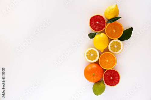 Close up image of juicy organic whole and halved assorted citrus fruits  green leaves   visible core texture  isolated white background  copy space. Vitamin C loaded food concept. Top view  flat lay.