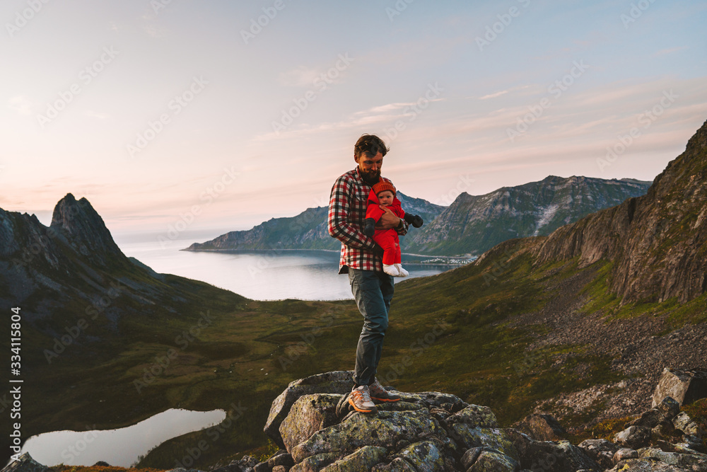 Fototapeta premium Travel family father hiking with baby outdoor in mountains vacations man with child healthy lifestyle adventure journey in Norway