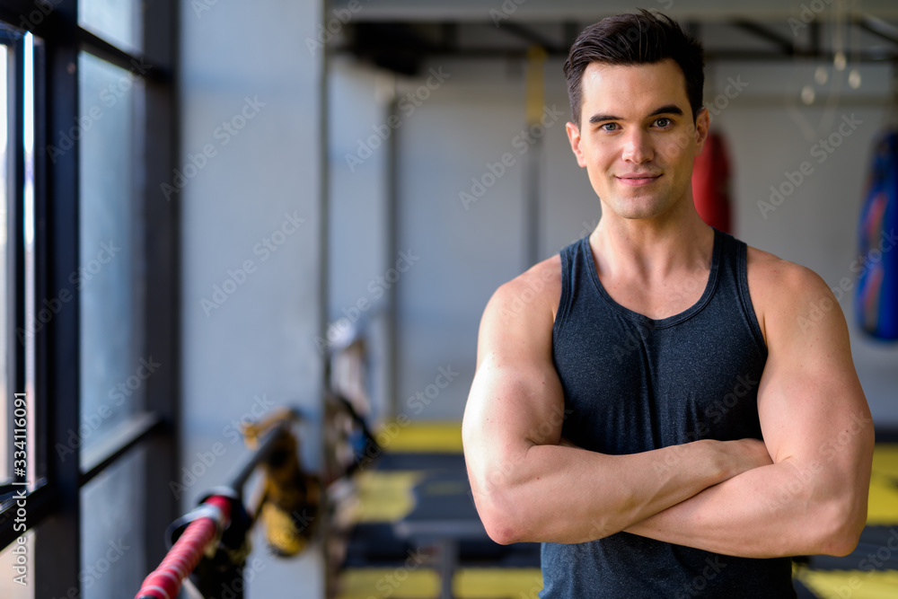 Young handsome man with arms crossed at the gym