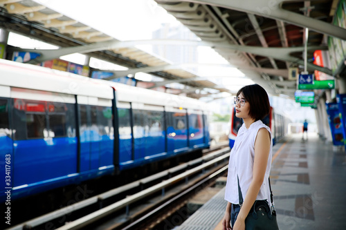 Asian young short hair woman waiting for arriving train on platform © Nattawat