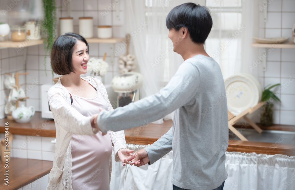 Joyful pregnant asian couple have fun, dancing next to window in kitchen at home, with copy space.health care and love of pregnancy mother’s day concept. Joyful pregnant asian couple have fun, dancing next to window in kitchen at home, with copy space.health care and love of pregnancy mother’s day concept.
