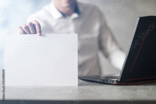 Miejsce na napis, karta w doni trzymana przez młodego mężczyzne w koszuli przy laptopie.