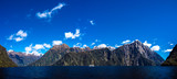Beautiful panorama of Milford Sound with Mitre Peak on the foreground and snow capped mountains in the background taken on a sunny spring day, New Zealand