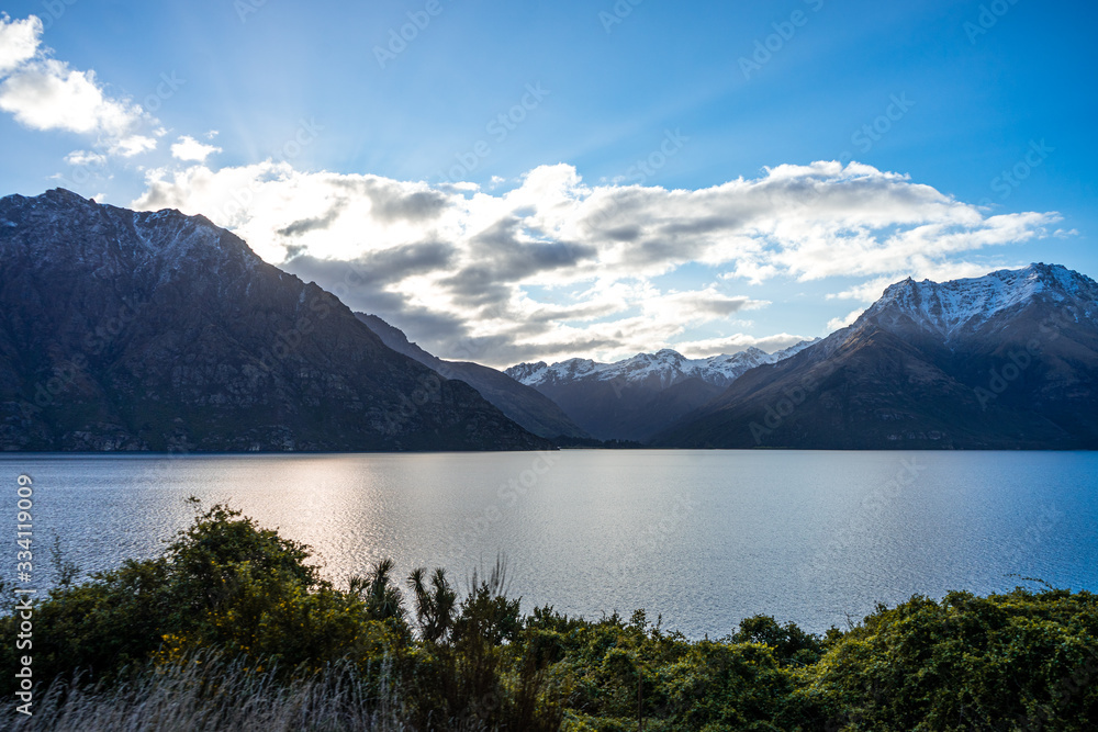 Gorgeous image of the snow capped mountains at the Wakatipu lake taken during an orange sunset in Queenstown, New Zealand
