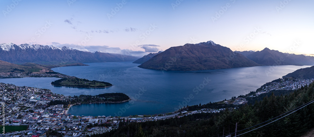 Gorgeous image of Queenstown with snow capped mountains in the background taken during an orange sunset from Skyline Queenstown, New Zealand