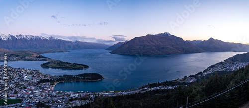 Gorgeous image of Queenstown with snow capped mountains in the background taken during an orange sunset from Skyline Queenstown, New Zealand