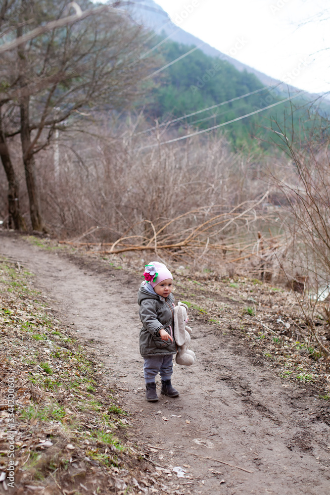Little girl walks along a forest path in the background of mountains Little girl walks along a forest path in the background of mountains