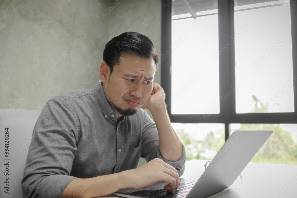 Serious face of Asian man working on laptop alone in the room. Serious face of Asian man working on laptop alone in the room.