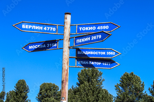 pillar with directions and signs to cities: Berlin, Tokyo, Moscow, Vladivostok, Beijing, Ulan Bator and distance in kilometers Altai in Russia