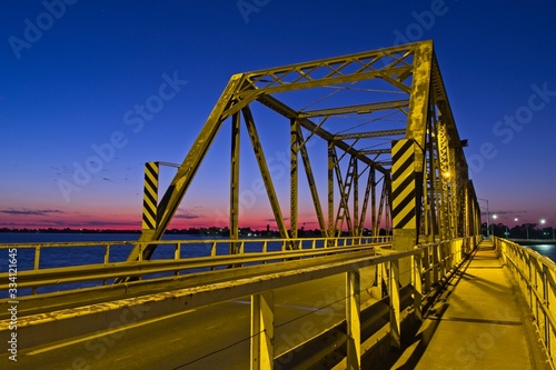 Mulwala Bridge looking yellow in the sunrise light, under a deep blue sky with a vibrant pink horizon.