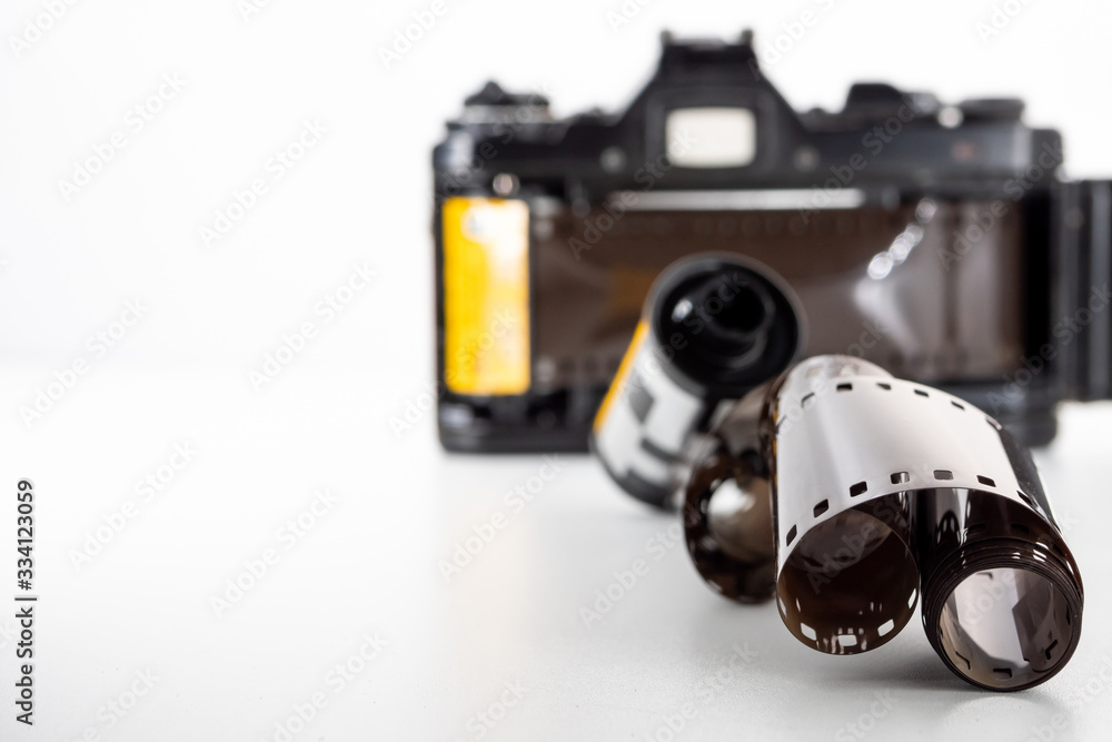 Single lens reflex camera and a film roll on a white background. Single lens reflex camera and a film roll on a white background.