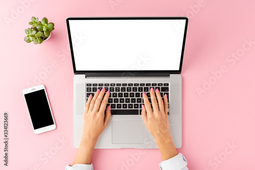 Female hands working on laptop with empty display. Office desktop with accessories. Top view