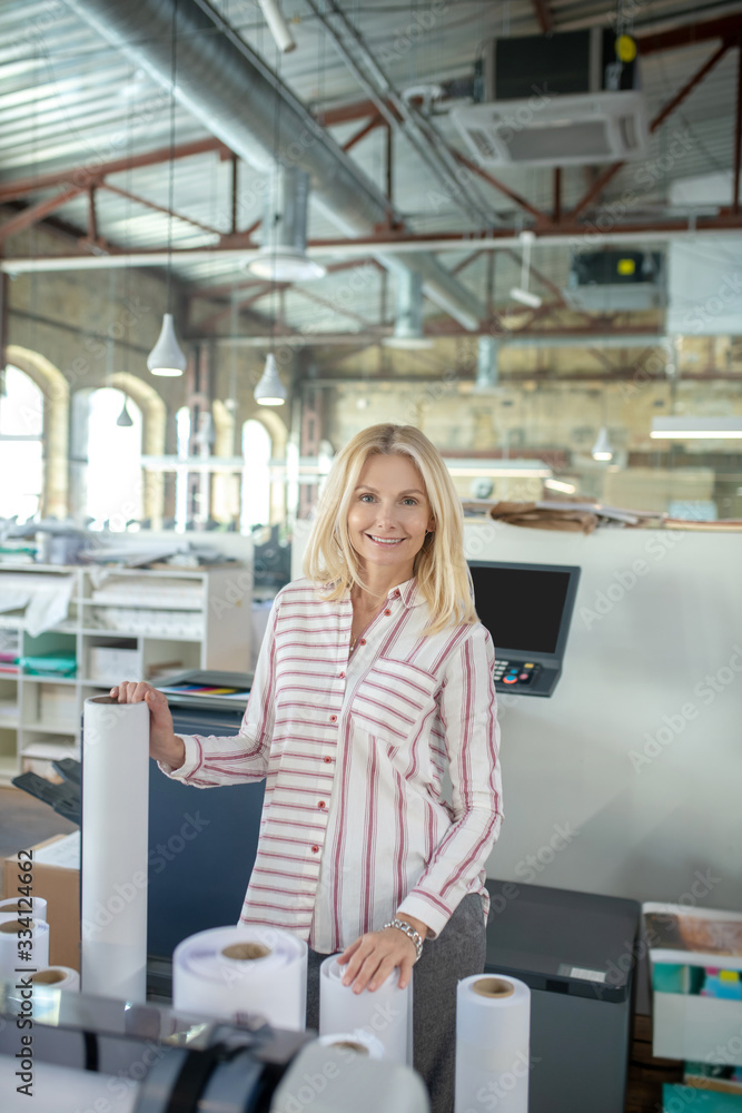 Fototapeta premium Blonde woman standing, holding paper rolls of different sizes