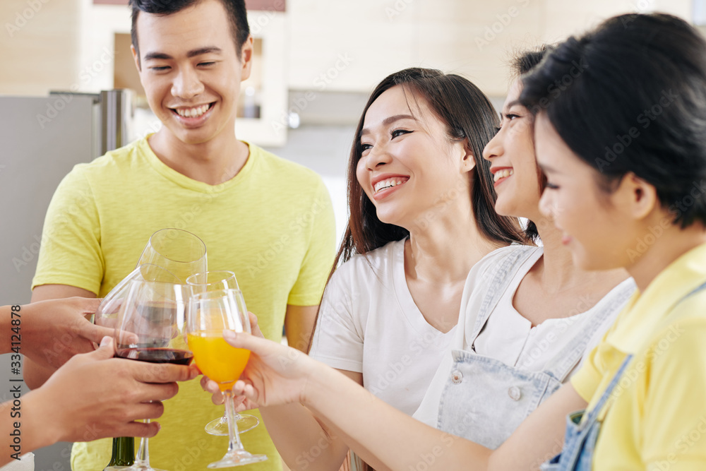 Cheerful young Vietnamese people gathered at house party for having some drinks and socializing Cheerful young Vietnamese people gathered at house party for having some drinks and socializing