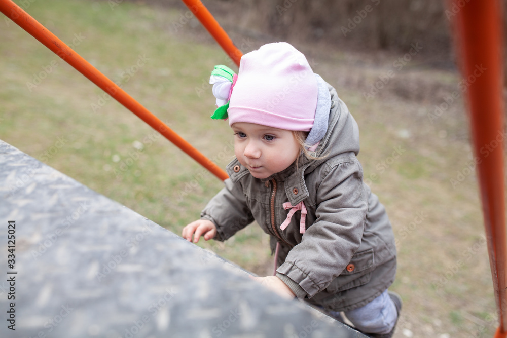 A little girl walk on a playground in an eco park against the background of a spring forest, A little girl walk on a playground in an eco park against the background of a spring forest,