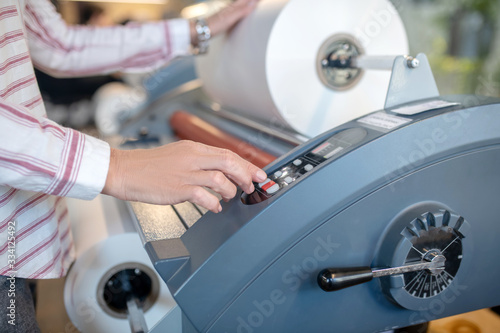 Female hands, pushing buttons, adjusting paper roll machine