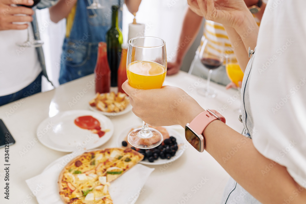 Young woman enjoying glass of orange juice and hot pizza at house party