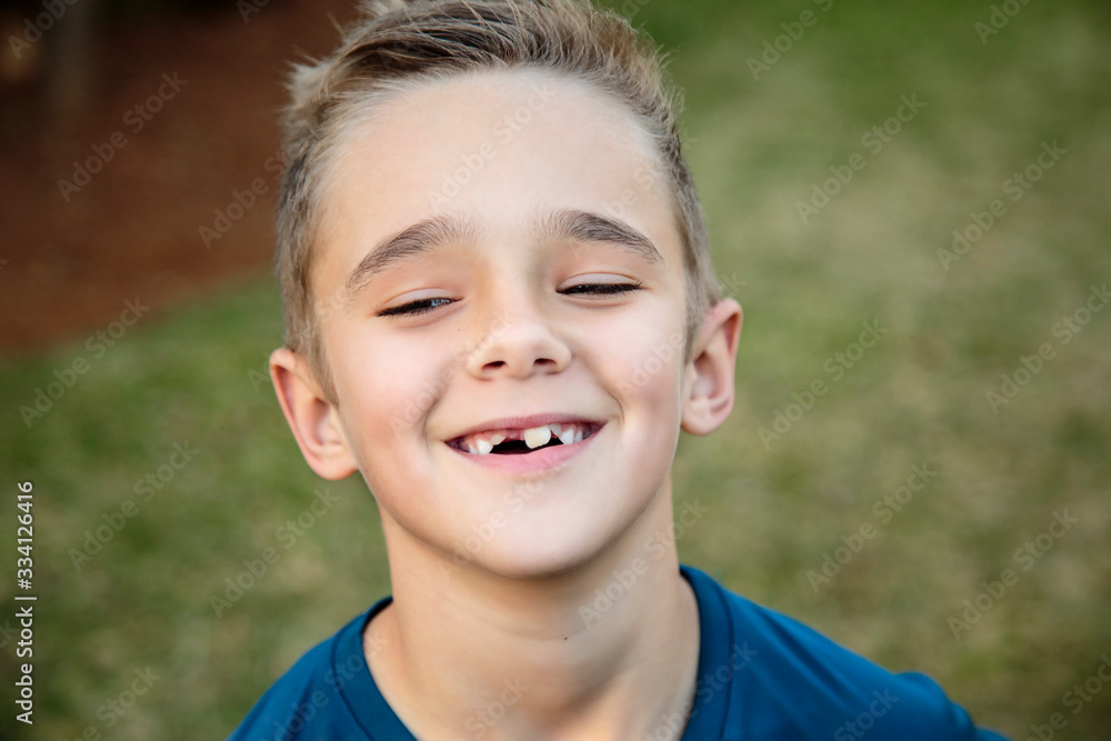 The Joy of Childhood: A Close-up of a Smiling Young Boy with a Toothy Grin and Tilted Head The Joy of Childhood: A Close-up of a Smiling Young Boy with a Toothy Grin and Tilted Head