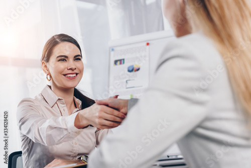 Recruiter smiling and shaking hands with employee at job interview in office