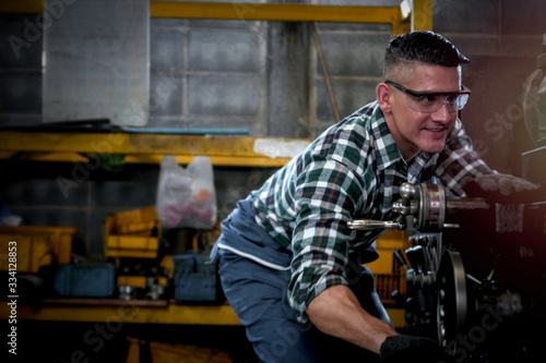 Industrial engineer worker wearing helmet and safe glasses operating with machinery at manufacturing plant factory, working with machine in industry concept