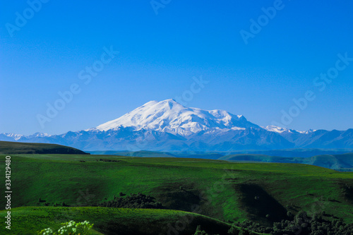 Dawn on the Gumbashi pass, view of mount Elbrus - the highest point in Russia. In summer, meadows bloom in Karachay-Cherkessia, and it always snows on the top of Elbrus photo