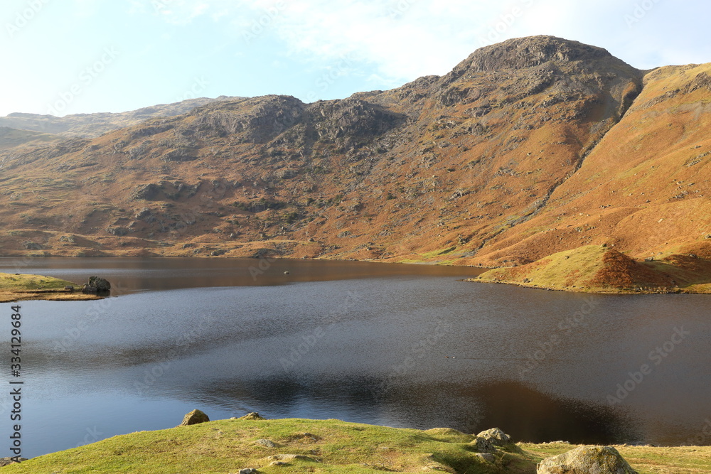 Beautiful Easedale Tarn in the English Lake District National Park surrounded by dramatic cliffs.