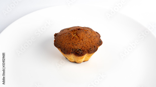 Sweet homemade cupcake with raisins on a white plate.