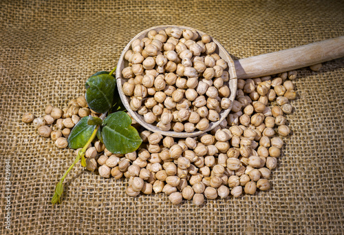    Chickpeas: composition of chickpeas with wooden container on a raw yuta canvas background. photo