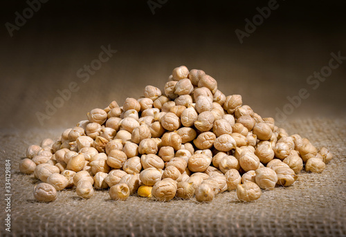 Chickpeas: composition of chickpeas with wooden container on a raw yuta canvas background. photo