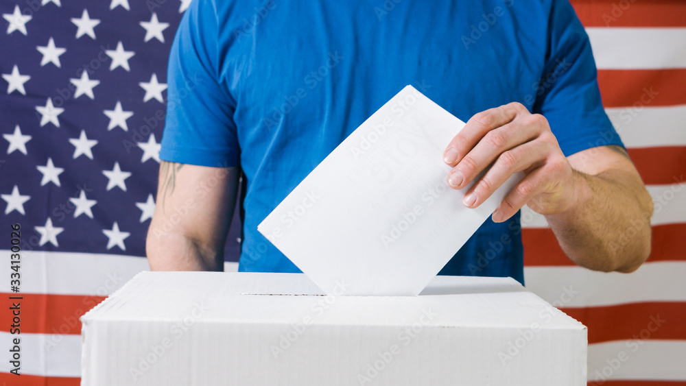 Persons Hand with ballot and voting box on Flag of USA Persons Hand with ballot and voting box on Flag of USA